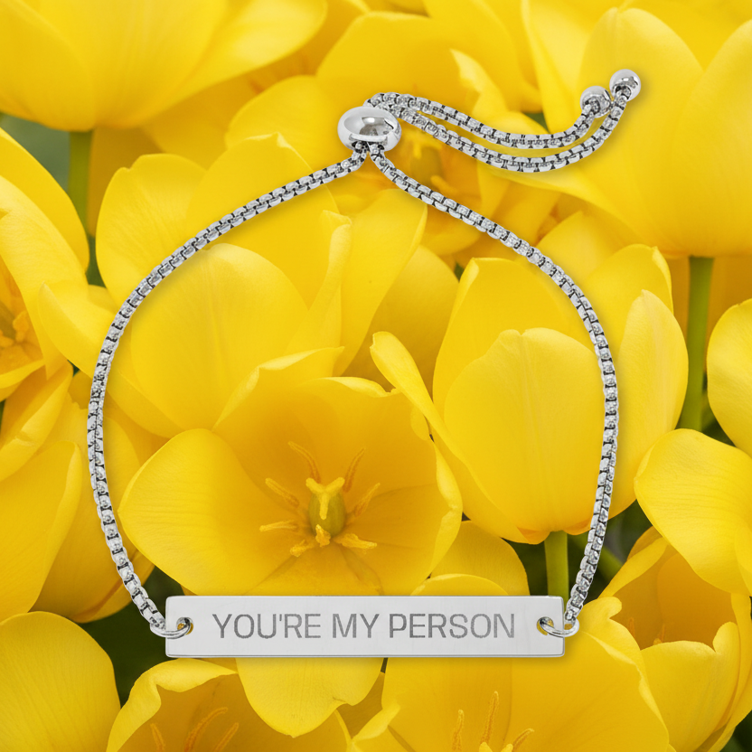 Silver bracelet with 'YOU'RE MY PERSON' message on yellow tulips