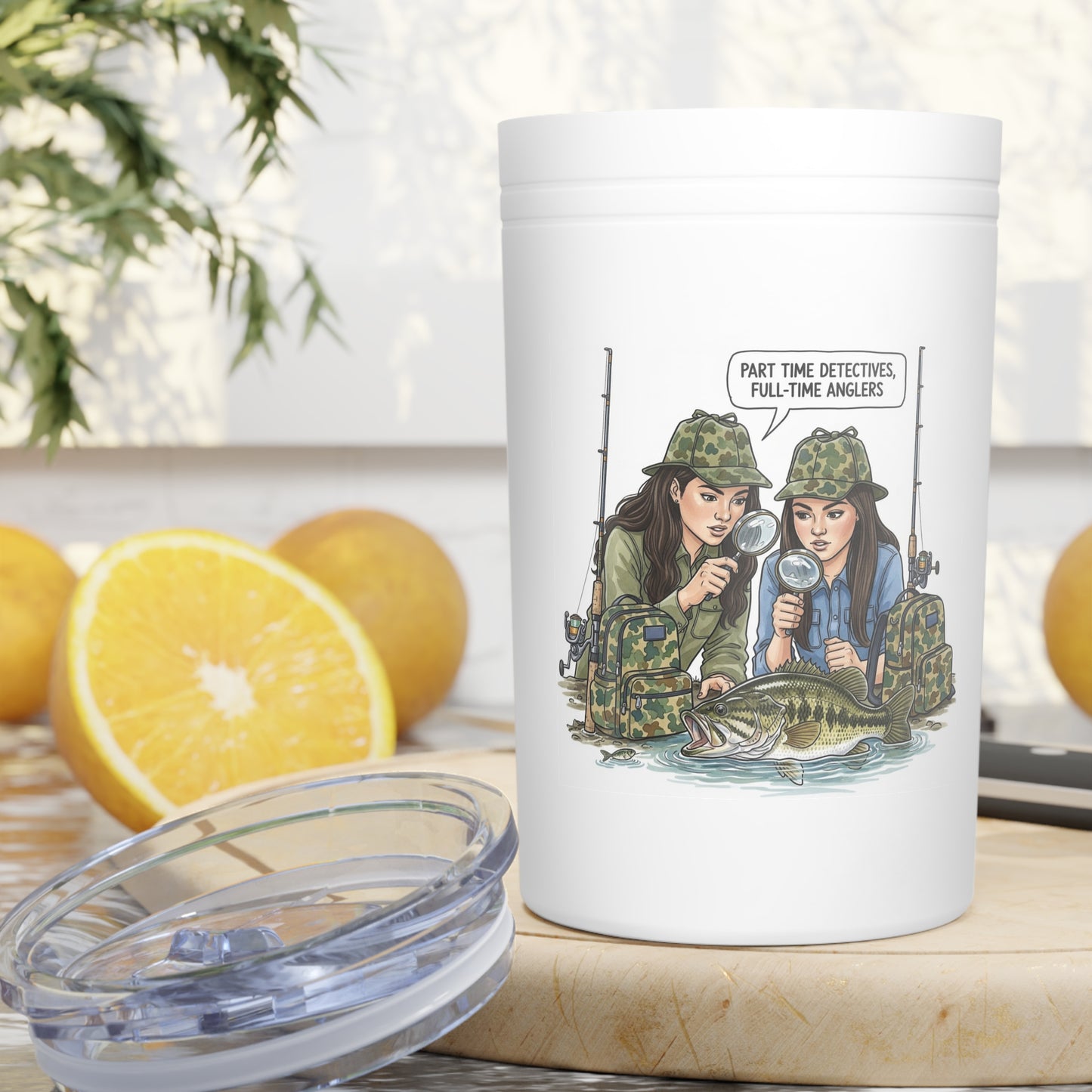 White tumbler with fishing-themed design on a table with lemons and a plant in the background