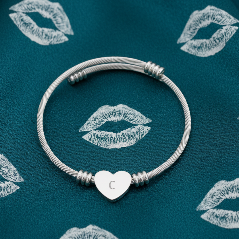 Silver bracelet with a heart-shaped charm with Initial "C" on a blue background with lip prints