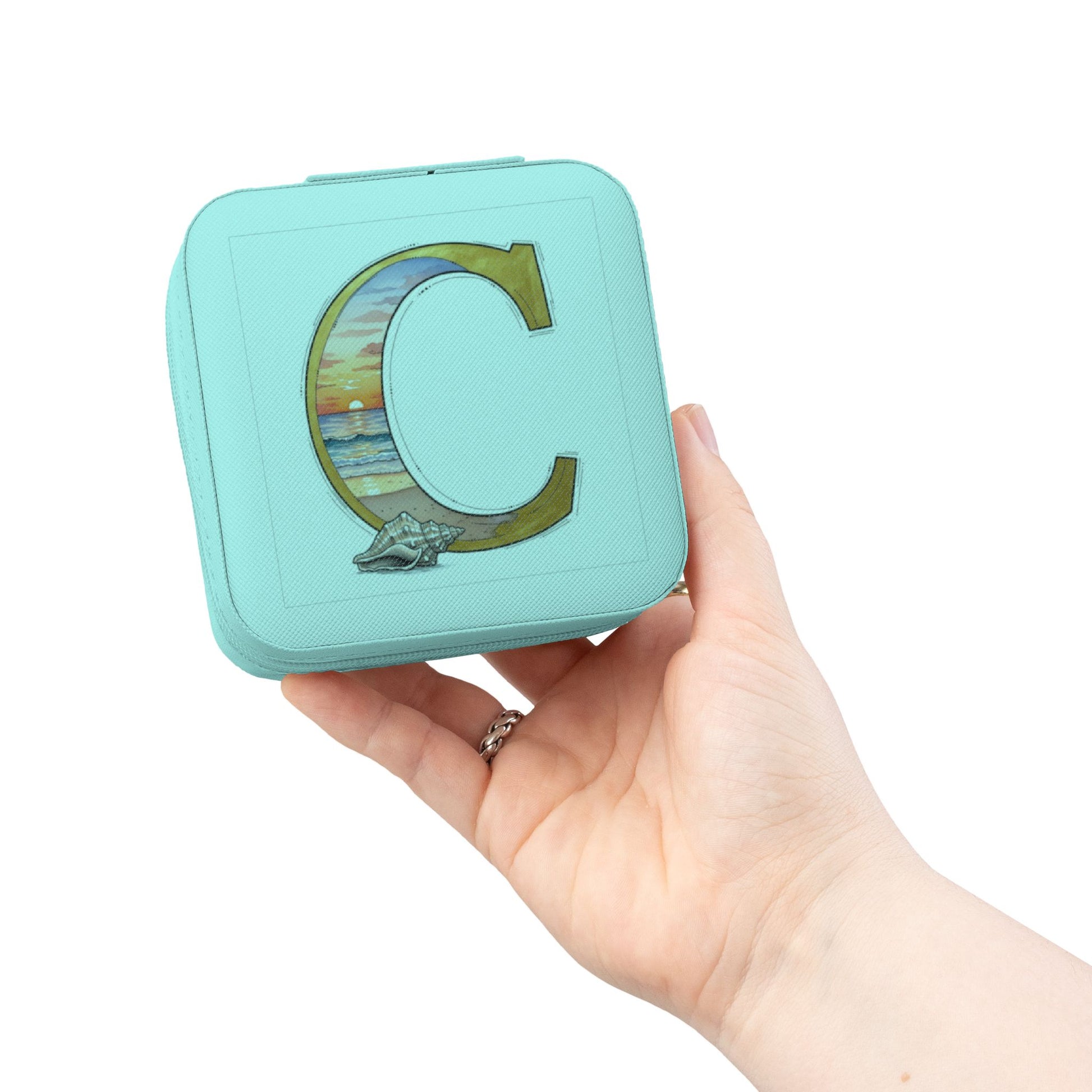 Turquoise square container with letter 'C' design held in a hand against a white background
