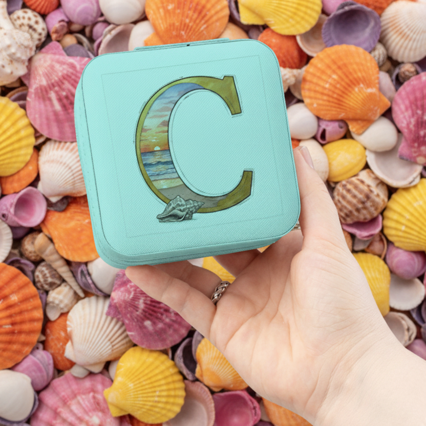 Turquoise square container with letter 'C' on a bed of colorful shells