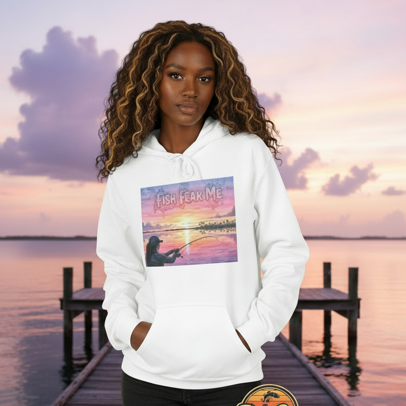 Person wearing a white hoodie with a sunset and fishing design, standing on a dock with a scenic background.