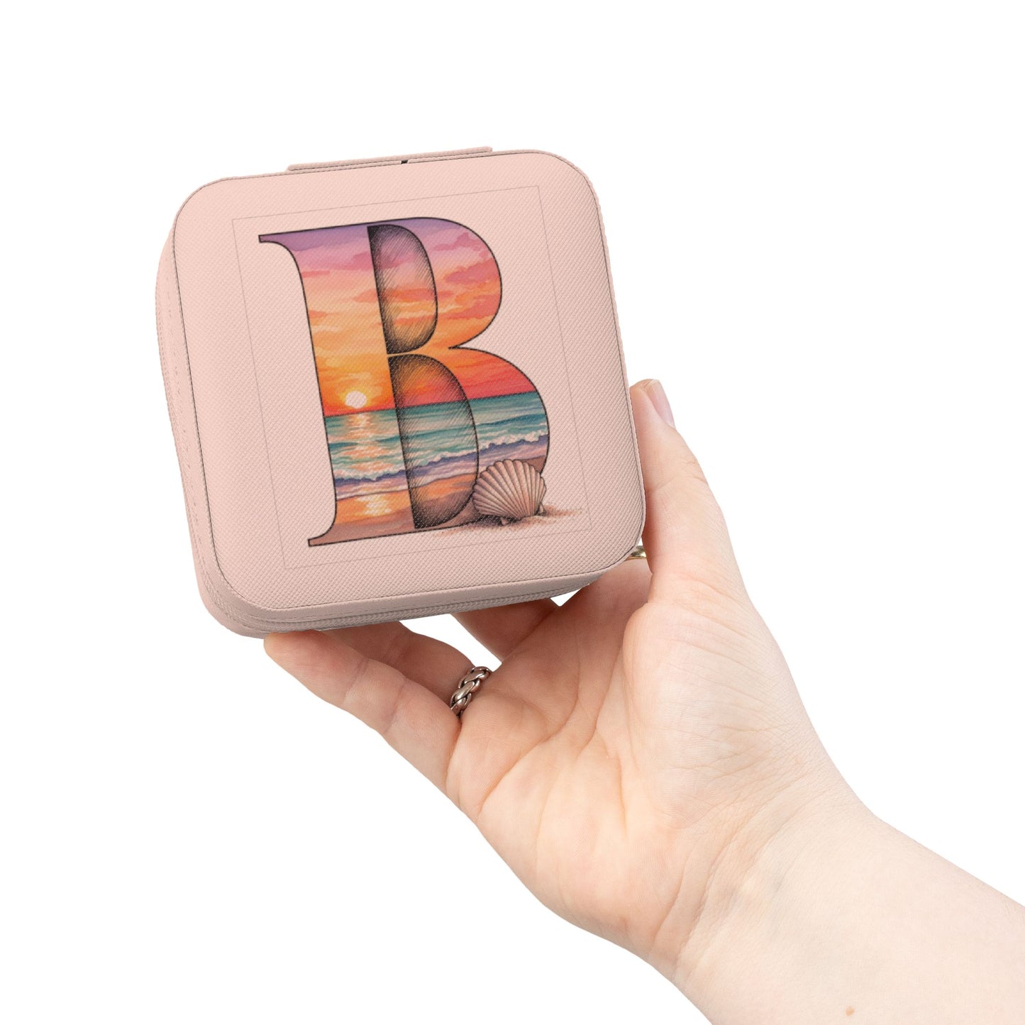 Hand holding a small pink box with a colorful 'B' design on a white background