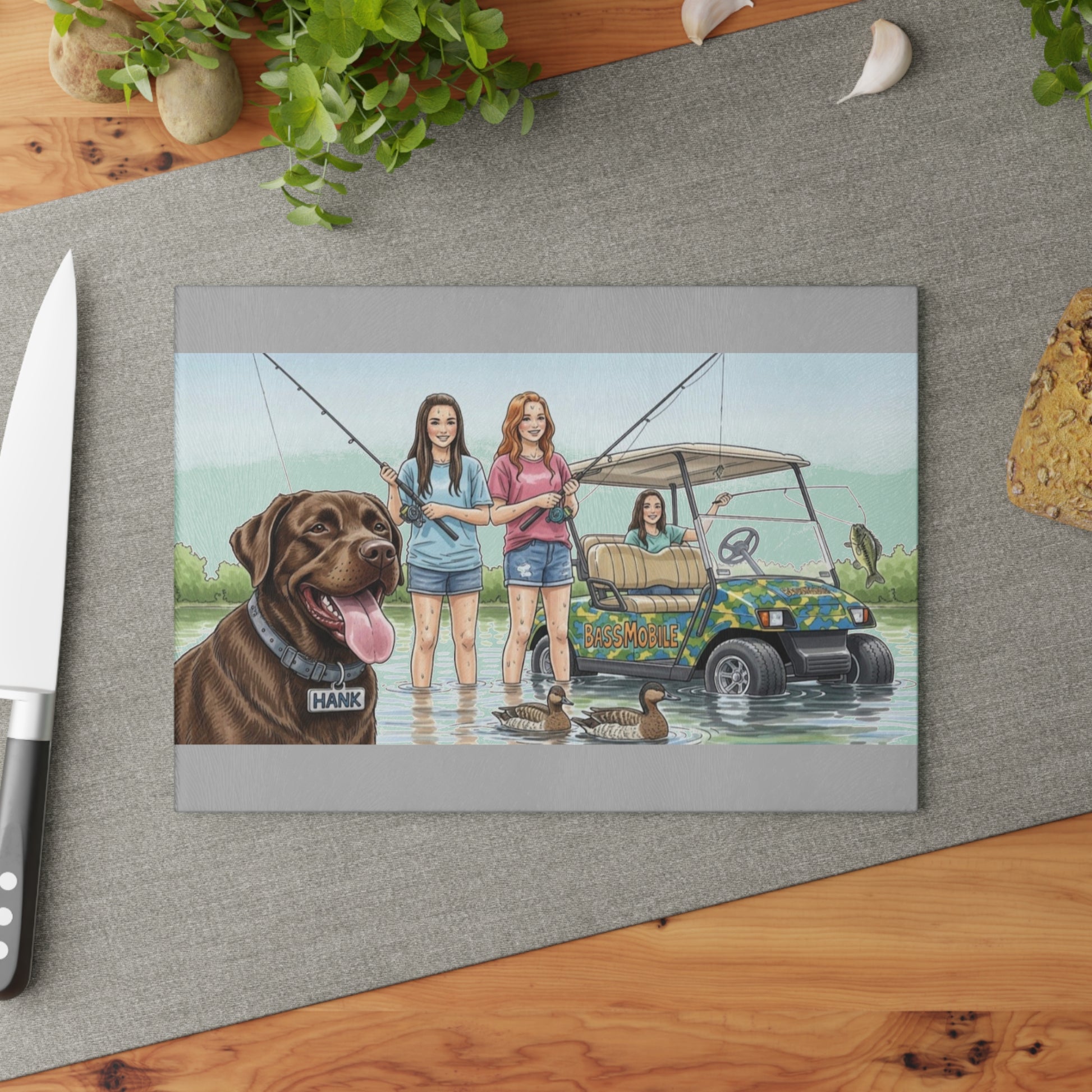 Glass cutting board with an Illustration of three people with a dog by a lake on a gray surface.
