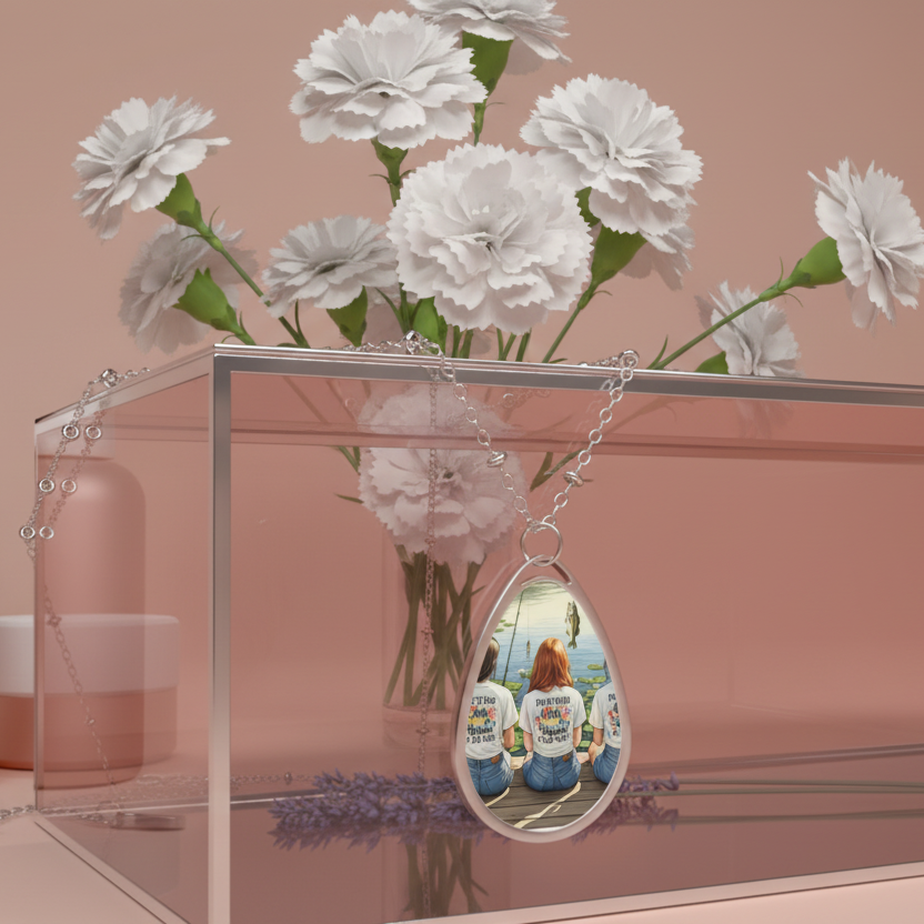 Clear acrylic stand with white flowers and a teardrop-shaped pendant necklace on a silver chain reflecting people wearing shirts.