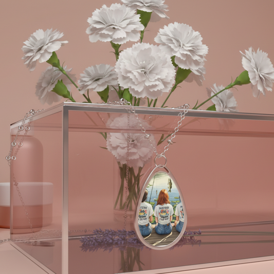 Clear acrylic stand with white flowers and a teardrop-shaped pendant necklace on a silver chain reflecting people wearing shirts.