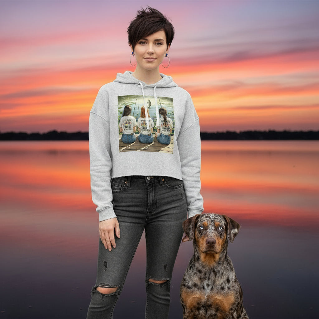 Person wearing a hoodie with a fishing graphic design of two women and a dog, standing next to a dog with a sunset in the background.