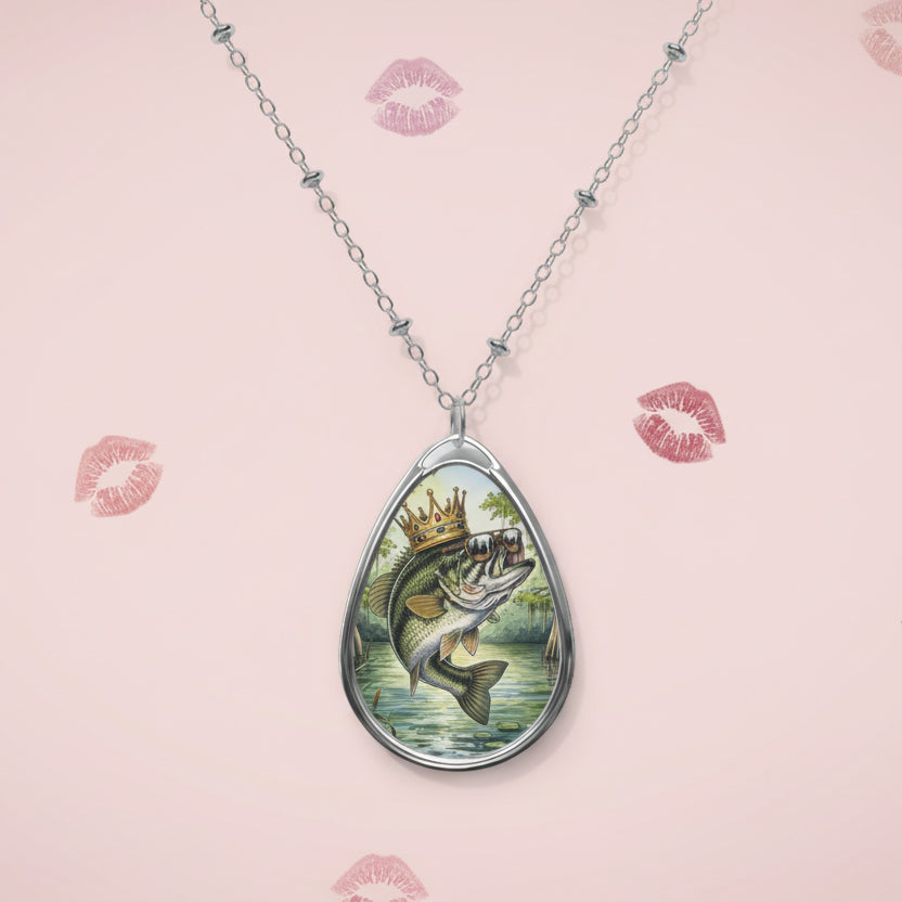 Teardrop-shaped pendant with a fish design on a pink background with lipstick marks.