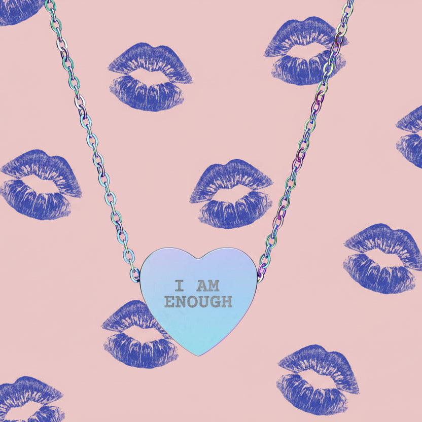 Necklace with a heart-shaped pendant displaying 'I AM ENOUGH' on a pink background with blue lip prints.
