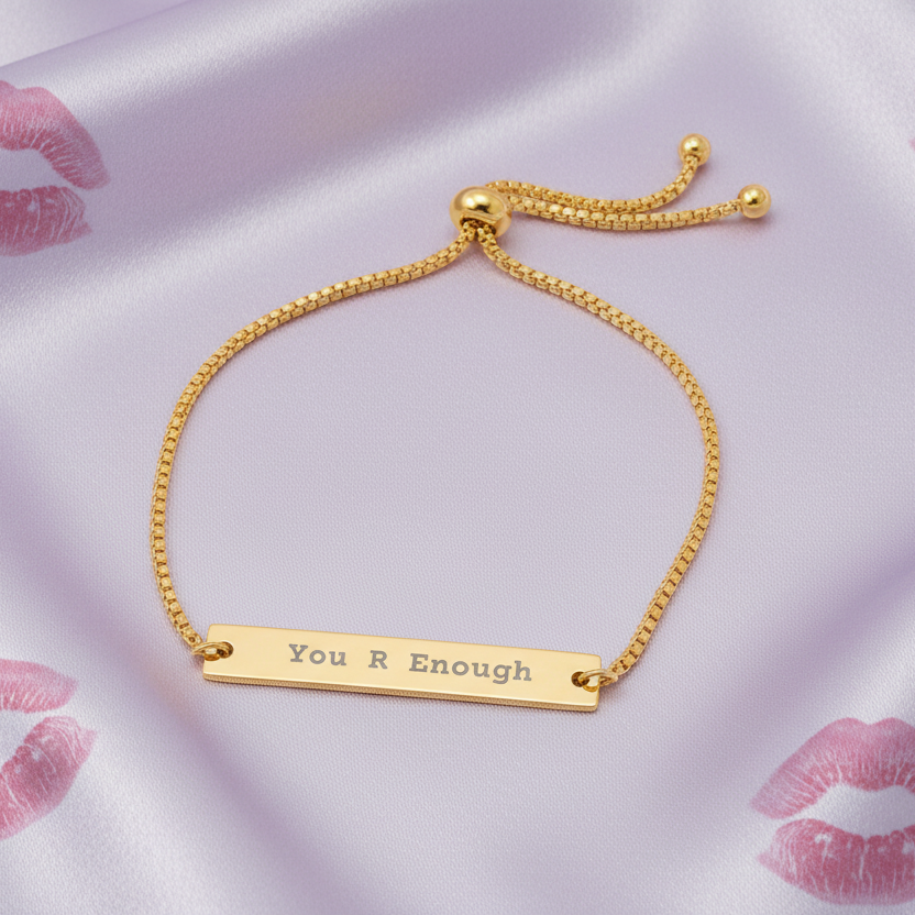 Gold bracelet with 'You R Enough' engraving on a satin background
