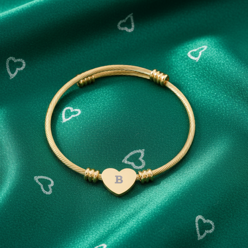 Gold bracelet with a heart-shaped charm on a green fabric background