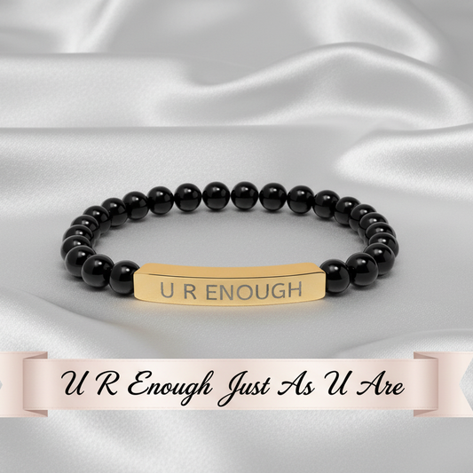 Black natural stone beaded bracelet with a gold tag on a white satin background
