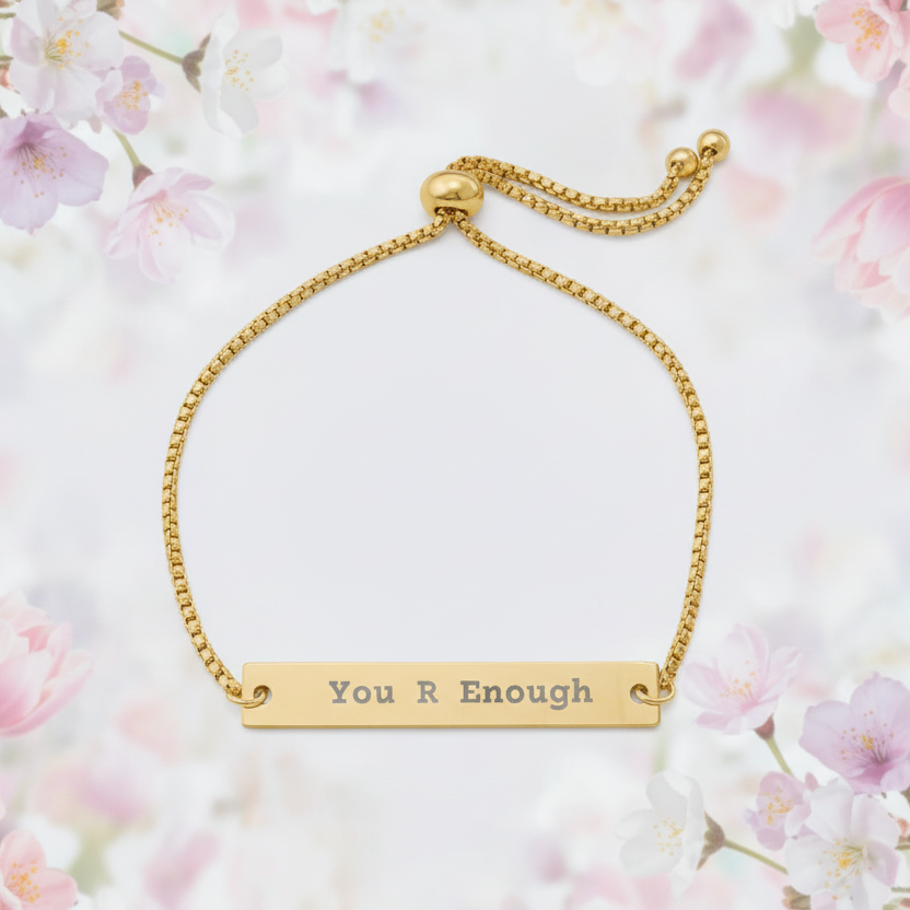 Gold bracelet with 'You R Enough' engraving on a floral background