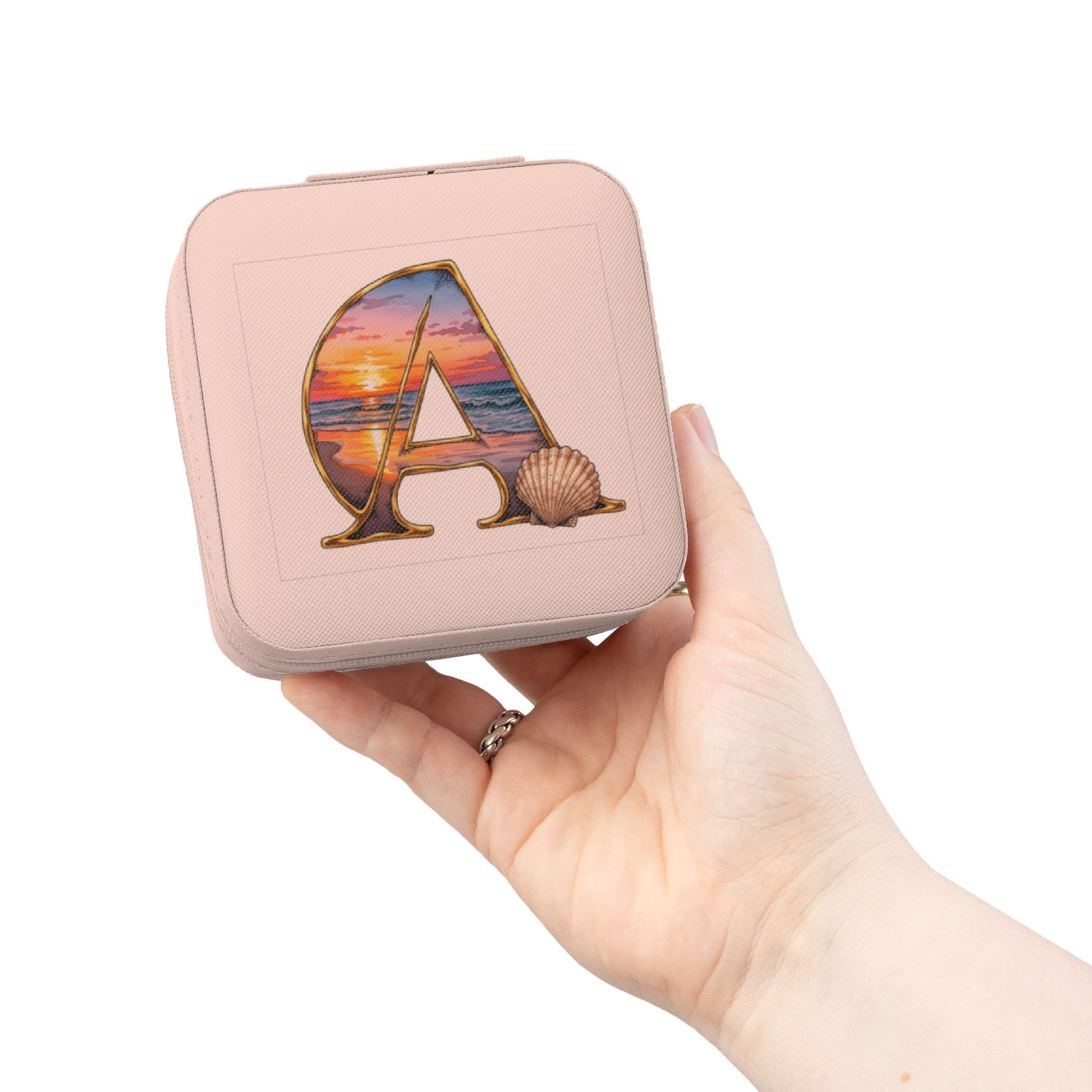 Pink jewelry case with 'A' design held by a hand on a white background