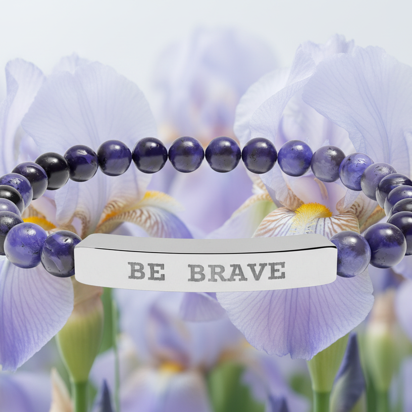 Natural Stone beaded bracelet with 'BE BRAVE' engraved on silver bar in front of purple flowers background 