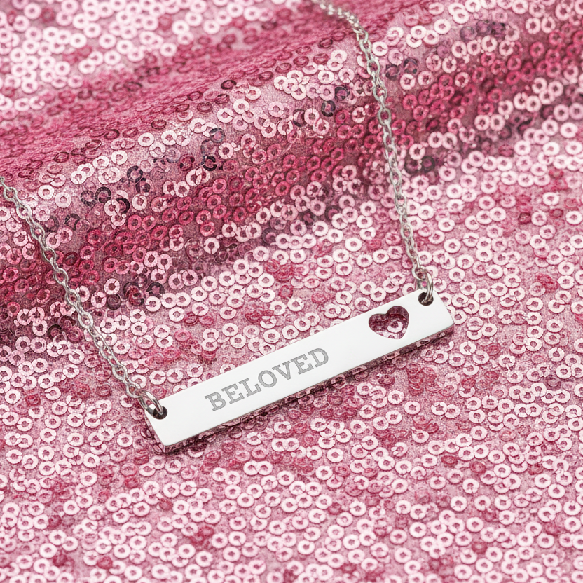Necklace with 'Beloved' pendant on a pink sequin background