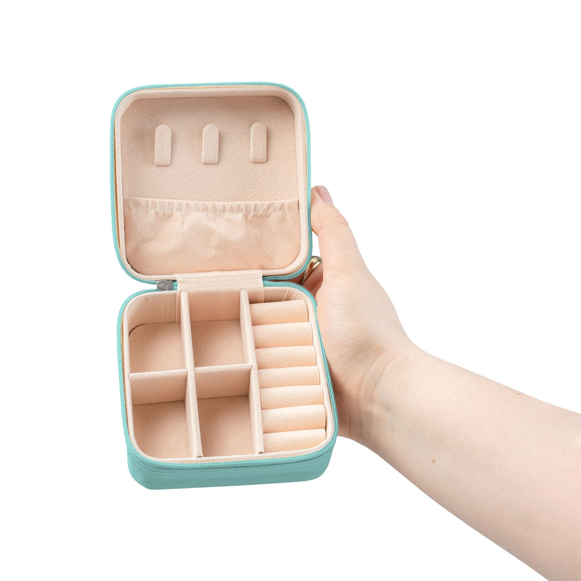 Hand holding a turquoise travel jewelry box with beige interior