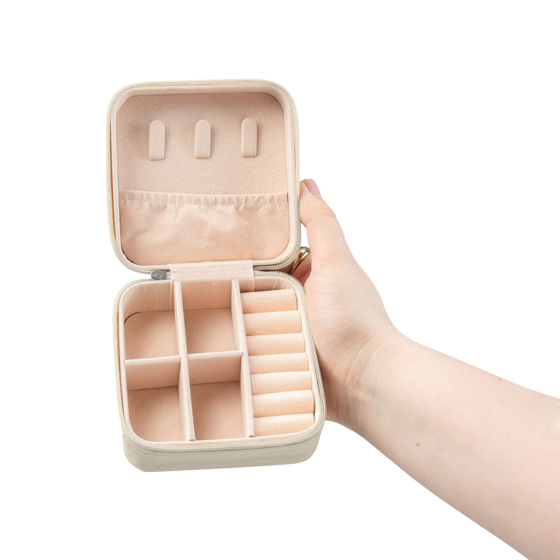 Jewelry travel case - Beige jewelry case with compartments held open by a hand on a white background