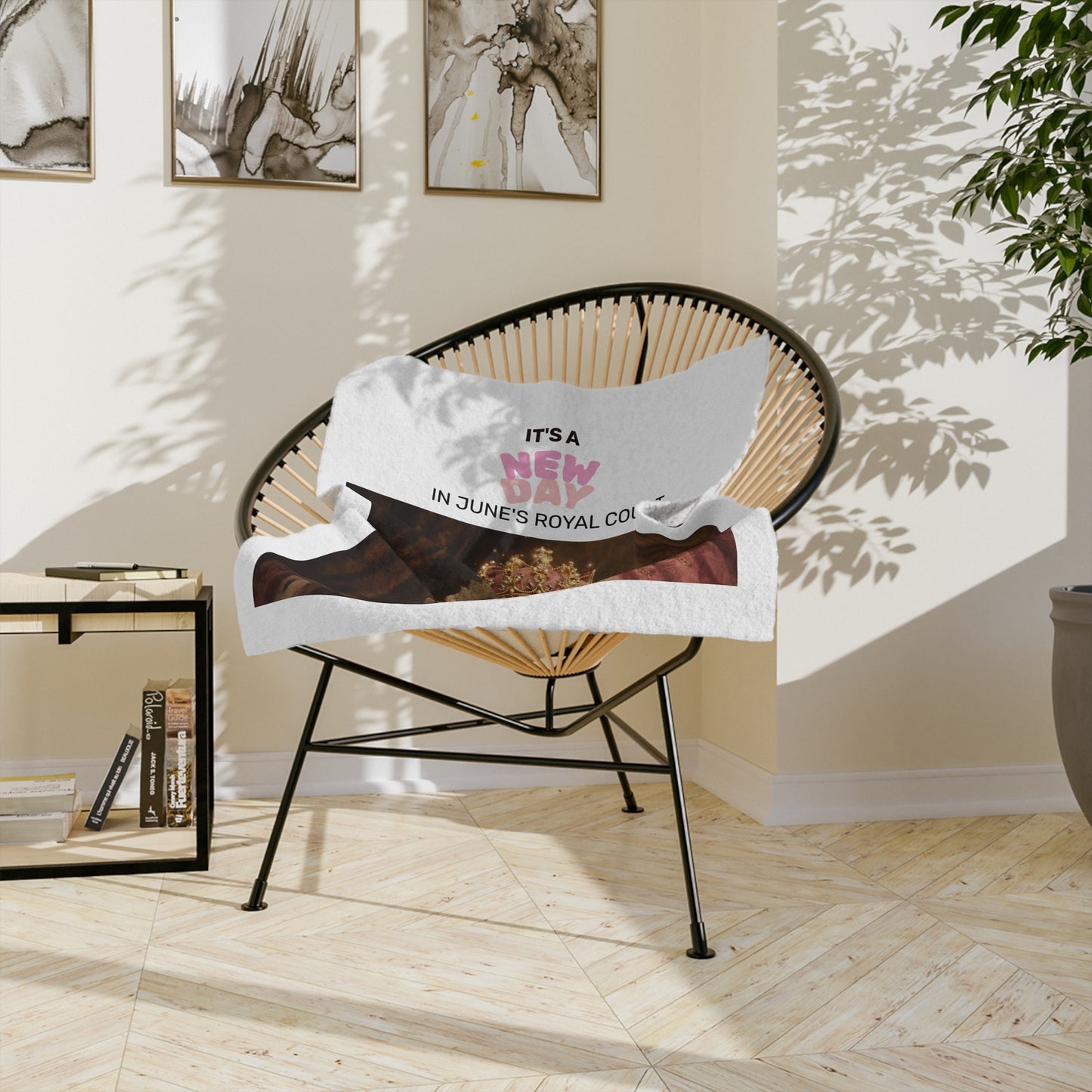 Queen June in regal attire with a crown and text 'It's a New Day in June's Royal Court' on a white background velvet lap throw on a chair in a sunlit room.