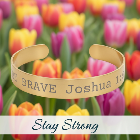 Gold bracelet with 'Be Brave Joshua 1:9' text in front of colorful tulips