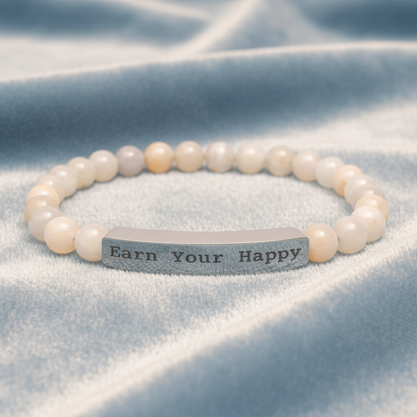 Natural Stone stretch beaded bracelet with a silver bar engraved with "Earn Your Happy" on a pale blue satin cloth