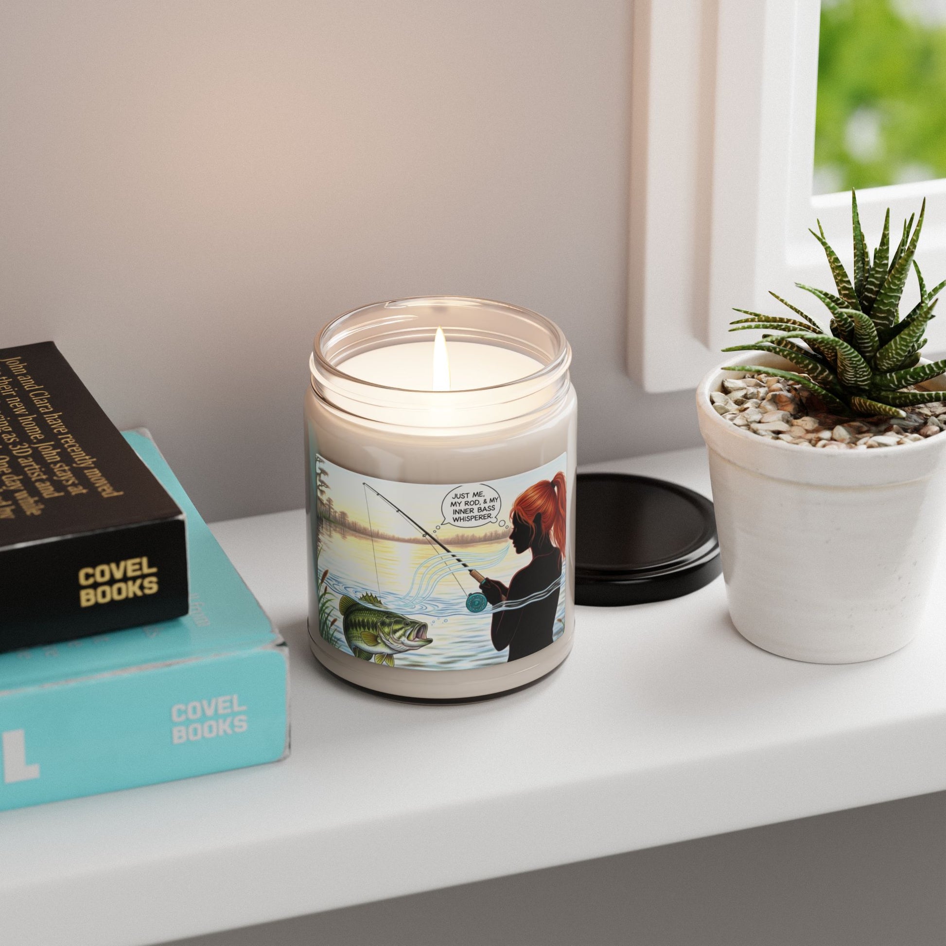 Candle with a scenic design on a shelf with books and a plant