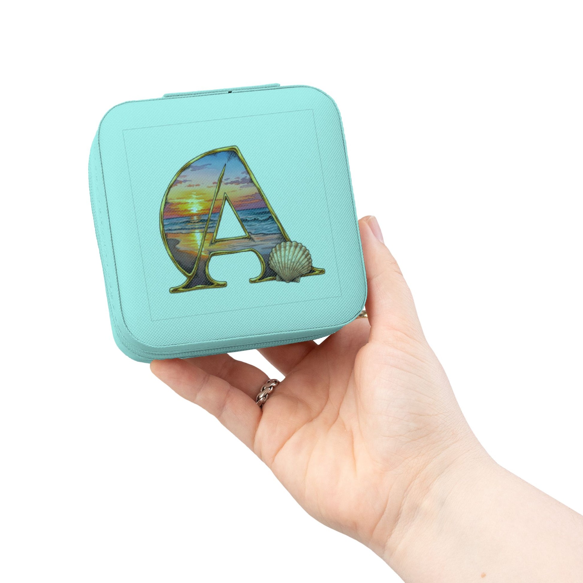 Turquoise jewelry box with 'A' design held in a hand against a white background

