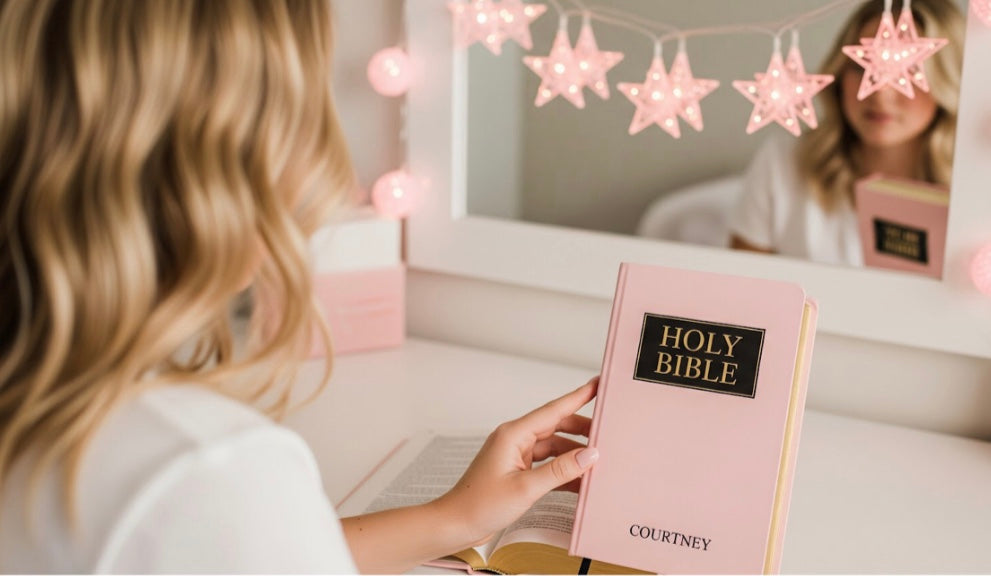 Person holding a pink Bible with 'HOLY BIBLE' and 'COURTNEY' on the cover, surrounded by star-shaped lights.