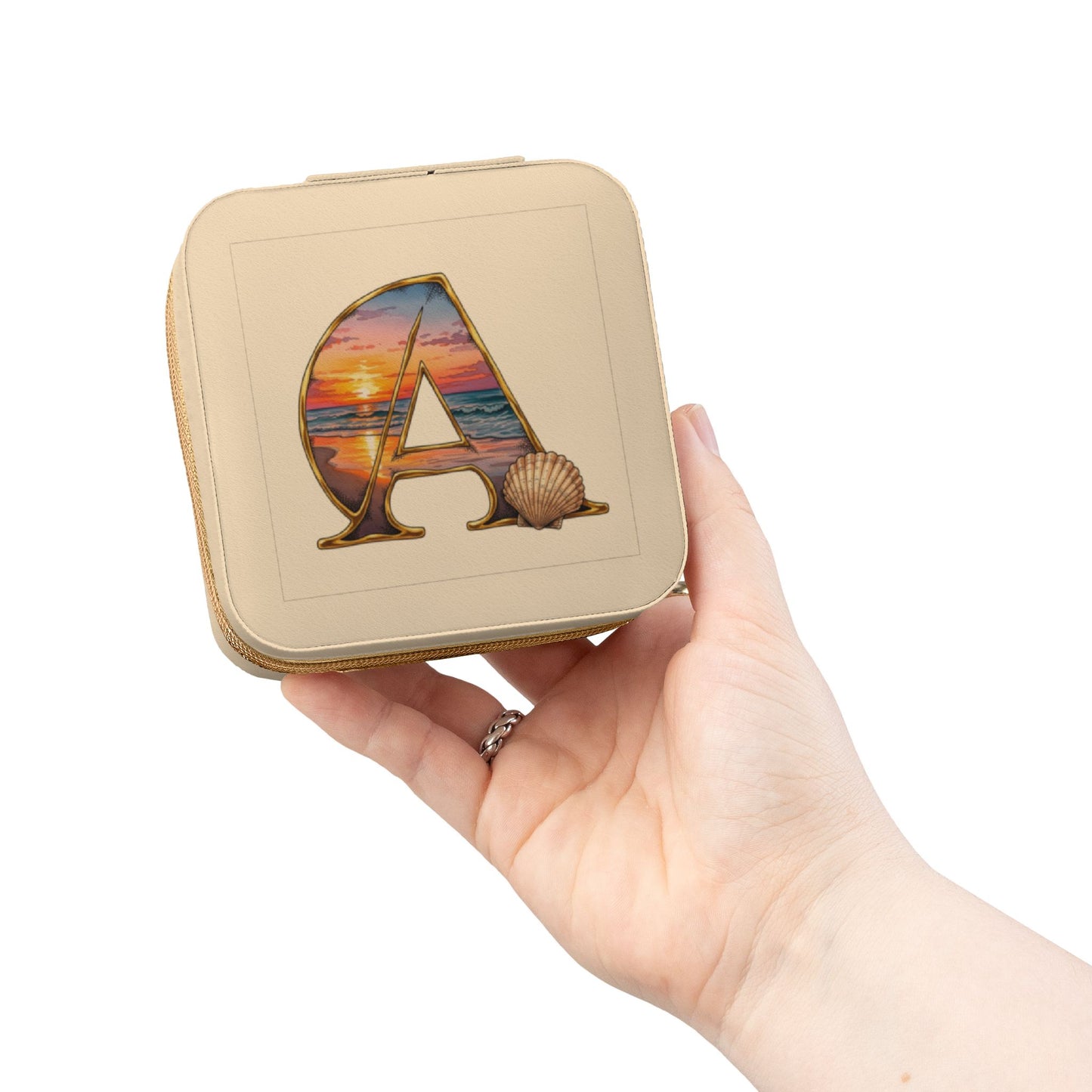 Hand holding a square tin with a decorative letter 'A' design on a white background